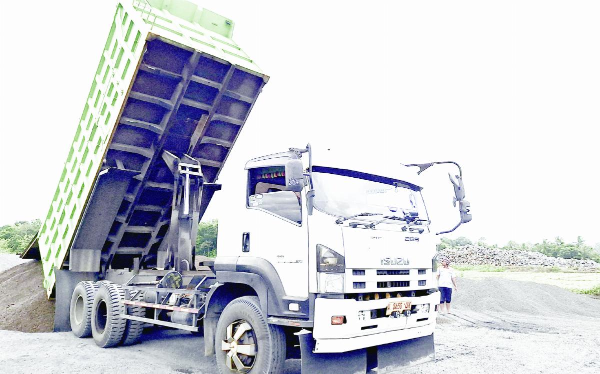 Dump truck membongkar material konstruksi